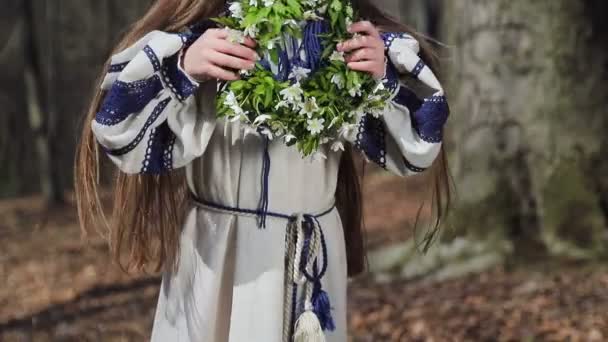 Ein kleines Mädchen im Wald nimmt einen Schneebesen mit weißen Waldblumen und legt ihn auf seinen Kopf — Stockvideo