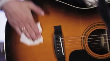 Gitarist toz gitar beyaz bez ovuşturuyor