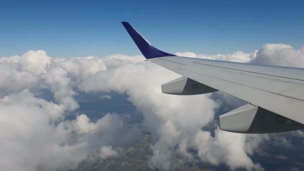 Blick aus dem Fenster des Flugzeugs. Die Tragfläche des Flugzeugs gegen den blauen Himmel und die weißen Wolken. Hintergrund — Stockvideo