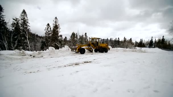 Ein Traktor räumt den Schnee vom Land, damit das Auto den Schnee von der großen Markierungstechnik reinigt — Stockvideo