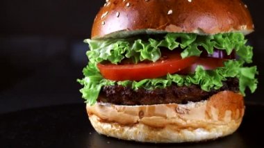 Siyah bir arka planda Burger yakın çekim. Yeşillik, domates ve tavuk burger maddeleri olarak. Hızlı gıda