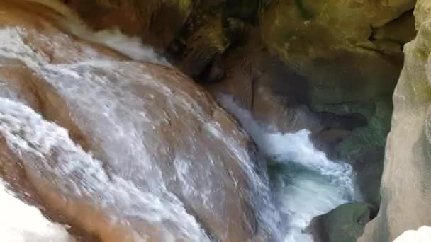 Strong water flow in the cave. A small waterfall underground. The flow of water breaks between the stones — Stock Video