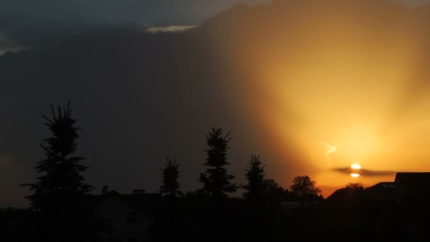 Maravillosa puesta de sol sobre la ciudad. El sol se pone y forma un cielo reluciente. Puesta de sol sobre los tejados y árboles — Vídeos de Stock