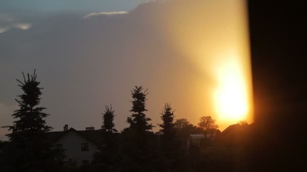 街の上に素晴らしい夕日。太陽が沈み、きらめく空を形成します。屋上や木々の夕日 — ストック動画