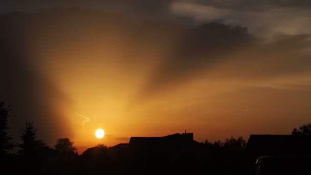 Maravilhoso pôr do sol sobre a cidade. O sol põe-se e forma um céu reluzente. Pôr do sol sobre os telhados e árvores — Vídeo de Stock