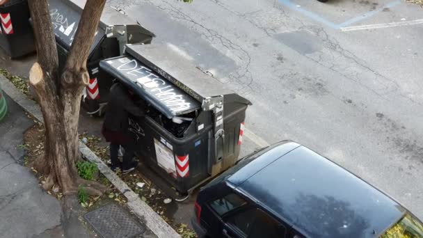 Bezdomovec kope do koše uprostřed ulice. hlad, utrpení. — Stock video