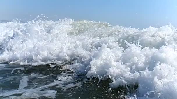 Grote bries golven close-up in slow motion, verplaatsen naar de kust. De spray van de Golf glinstert in de zon en giet langzaam, raakt elkaar aan en valt op het water. — Stockvideo