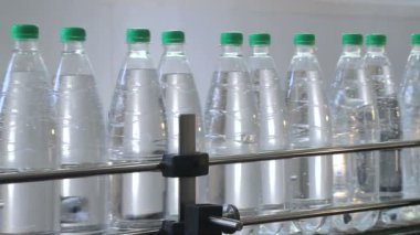 beyaz plastik şişeler, maden suyu ile dolu ve yeşil kapaklar ile tıkanmış su şişeleme hattı üzerinde durmak