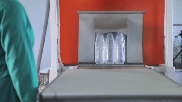 Emballage automatique de bouteilles en plastique avec film dans la presse à température. Emballage des bouteilles pour un transport ultérieur . — Video