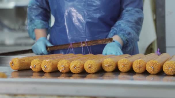 Un empleado, un carnicero, cuelga salchichas frescas y recién hechas en los estantes para seguir disparando en el horno. . — Vídeos de Stock