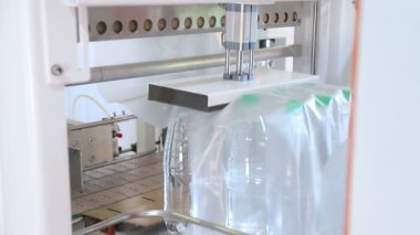 Sıcaklık presi film ile plastik şişe otomatik ambalaj. Daha fazla taşıma için şişelerin ambalajlama.