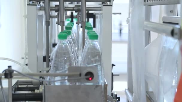 Automatische verpakking van plastic flessen met film in de temperatuur pers. Verpakking van flessen voor verder transport. — Stockvideo