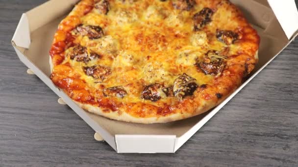 Eine Hand schließt eine Pappschachtel, in der eine duftende frisch gebackene Pizza liegt. Lieferung von Pizza im Karton. — Stockvideo