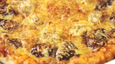 Lezzetli taze pişmiş İtalyan pizza, yakın çekim, dönen bir platform üzerinde dönüyor