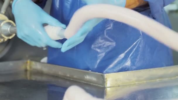 Productiemedewerker in blauwe rubberen handschoenen, maakt worst. Een close-up van een worst wordt gemaakt door een werknemer — Stockvideo
