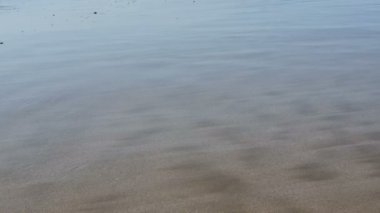 Dalgalar kıyıya yaklaşıyor. Deniz suyu seviyesi gelgitte yavaşça yükseliyor. Altın kumu kaplayan dalgalar sahili ele geçiriyor.