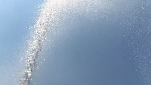 Against the background of the blue sky with white clouds, a jet of water in slow motion, sprinkles drops around. Background — Stock Video