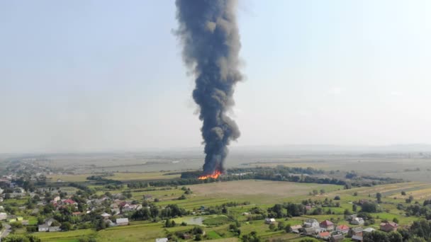 Flygfoto svart rök stiger högt upp i skyn. Brand utanför staden. — Stockvideo