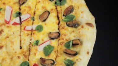 En üstten siyah arkaplan manzaralı yengeç çubuklu pizza.