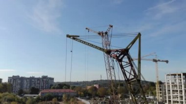 Mavi gökyüzünün arka planında inşaat vinçleri ve inşaat vincinin arkasına gizlenmiş parlak güneş