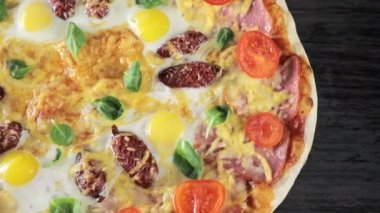 Peynirli domatesli, sosisli ve yumurtalı bir pizzanın yakın plan çekimi.