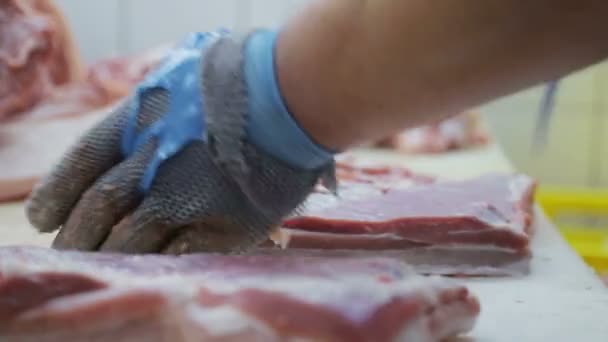 Nahaufnahme Arbeiter mit einem speziellen Metallhandschuh zum Schutz schneidet Fleischstücke. Entbeinung der Schweinefleischproduktion — Stockvideo