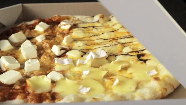 A pizza para o plano original de quatro queijos, que está na embalagem, girando em torno de si . — Vídeo de Stock