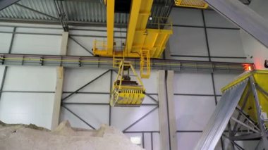 Devasa bir radyo kumandalı kova, kumları yakalar ve büyük bir kum deposuna döker..