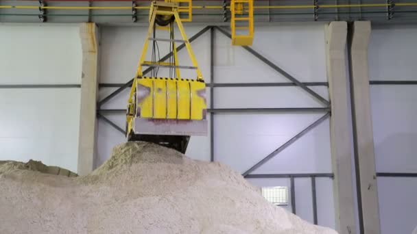 Un enorme cubo controlado por radio, agarra la arena y la vierte en un gran hangar de almacenamiento de arena . — Vídeos de Stock