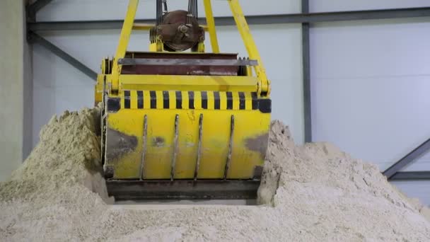 Un enorme cubo controlado por radio, agarra la arena y la vierte en un gran hangar de almacenamiento de arena . — Vídeos de Stock