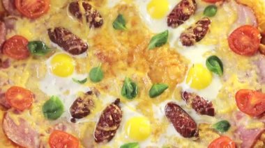Peynirli domatesli yakın plan pizza, sosis ve yumurta, kendi etrafında dönüyor, yukarıdan manzara