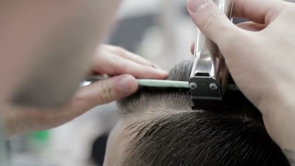 Стилістичний перукар, використовуючи затискач і гребінець, вирізає чоловіка крупним планом . — стокове відео