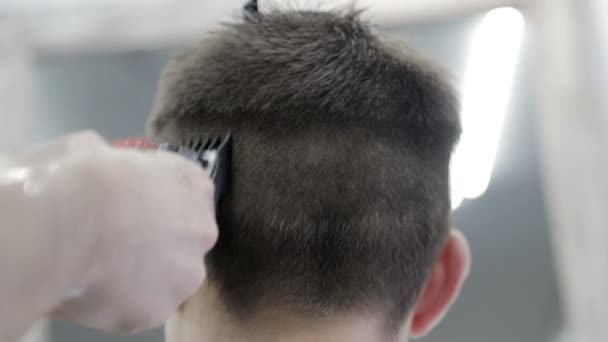Pánský účes v holičství. Detailní záběr mistra stříhání muže s černými vlasy s výstřižkem. — Stock video