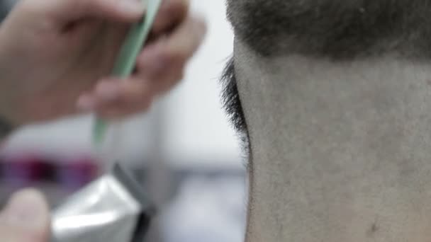Stylist frisör, med hjälp av en clipper och kam, skär sin man närbild. — Stockvideo