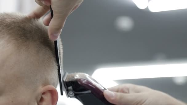 Стилістичний перукар, використовуючи затискач і гребінець, вирізає чоловіка крупним планом . — стокове відео