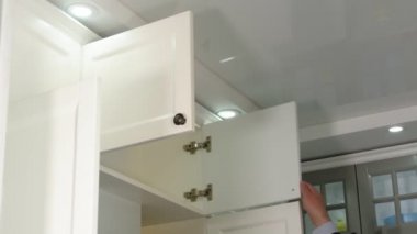Erkek eli yatağın başucundaki masayı açar. Beyaz, parlak bir mutfakta boş bir komodin..