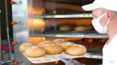 Şef fırından yeni pişmiş fırın ürünlerini çıkarıyor. Fırında pişmiş ekmek fırından çıkarılır..