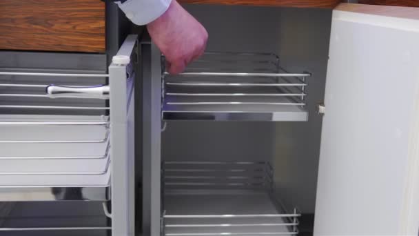 Un homme ouvre une cargaison d'angle pour la cuisine. Chargement vide dans l'armoire de cuisine . — Video