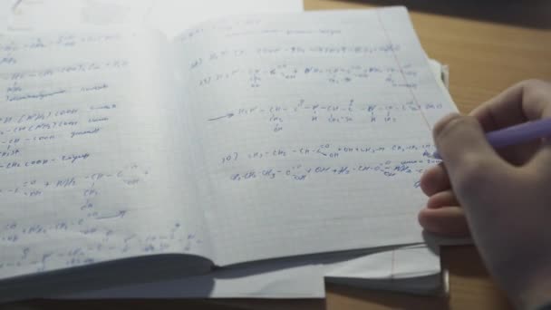 Muž řeší matematické problémy v notebooku a připravuje se na trénink. Muž píše s perem vzorec v zápisníku zblízka. — Stock video