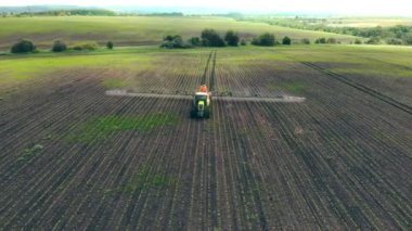 Hava manzaralı tarım makineleri yeşil alana böcek ilacı püskürtüyor, tarımsal doğal mevsimsel bahar çalışmaları. Tarım traktörü sahaya püskürtücü püskürtüyor.