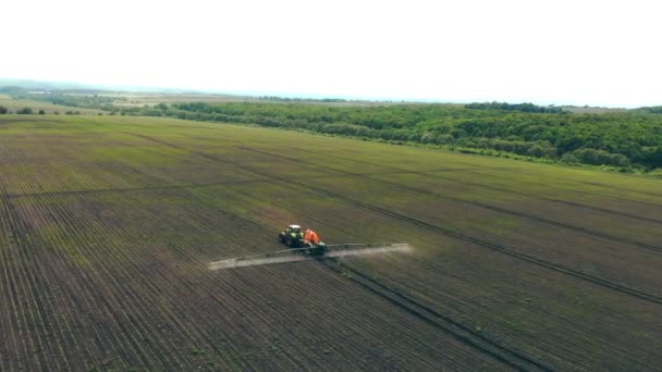 Flygfoto Farm maskiner besprutning insekticid till det gröna fältet, jordbruk naturliga säsongsbetonade våren verk. Besprutning av jordbrukstraktorer på fältet med spruta — Stockvideo