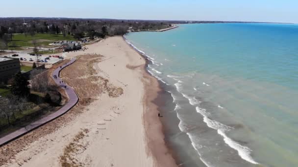 Menschen flanieren am Wochenende am Ufer des Michigansees in Illinois. Blick von der Drohne auf den Strand und die Böschung des Großen Sees. — Stockvideo