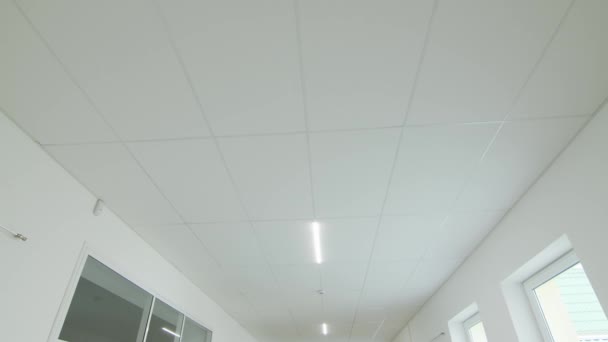 Movimiento de la cámara y mirar hacia arriba, techo blanco con iluminación. POV — Vídeos de Stock