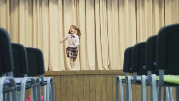 Ragazzina sul palco in una sala senza persone. la ragazza ruota intorno a se stessa . — Video Stock