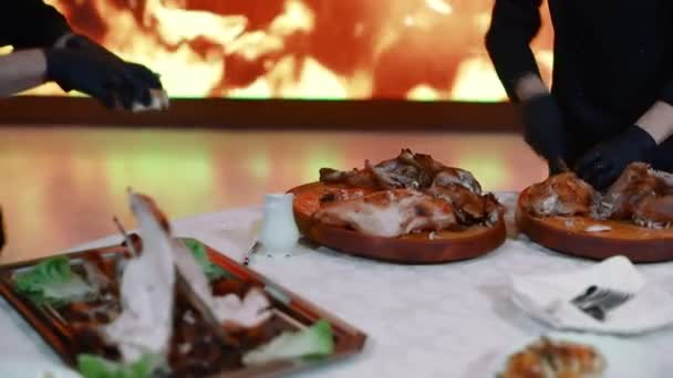 Gli chef tagliano carne appena cotta sullo sfondo di un grande schermo con un fuoco artificiale. Ambiente discografico. Luce di diversi colori illumina la scena . — Video Stock
