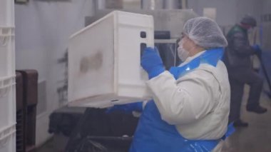Fabrika işçisi otomatik çamaşır makinesine boş plastik kutular koyar. Plastik kutular