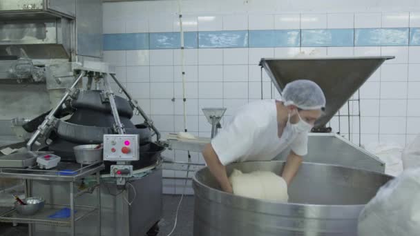 Bäckereiproduktion. Ein Bäckereiarbeiter füttert den Teig in einen automatischen Teigzuführautomaten in die Teigproduktfertigungslinie. — Stockvideo