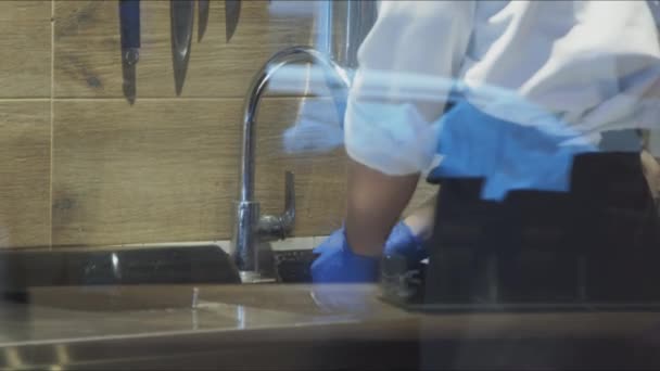 Посмотреть через стекло на рабочего, который моет посуду — стоковое видео