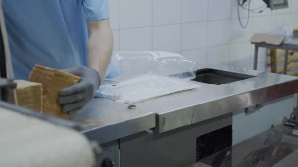 Хлебопекарня упаковывает нарезанный хлеб в пластиковые пакеты. Производство и упаковка хлеба . — стоковое видео
