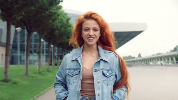 Porträt einer hübschen kaukasischen Frau mit schwarzem Haar, die in die Kamera lächelt. Mädchen auf der Straße vor dem Hintergrund moderner Interieurs, die in die Kamera lächeln. — Stockvideo
